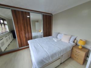 1 dormitorio con 1 cama grande y espejo en Bungalow in leafy area, en Upminster