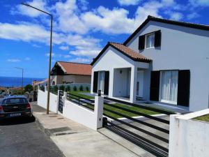 una casa blanca con un coche aparcado delante de ella en Sons da Ribeira, en Povoação