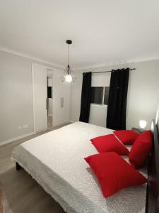 um quarto com uma grande cama branca com almofadas vermelhas em Sons da Ribeira em Povoação