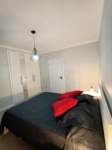 1 dormitorio con 1 cama grande con almohadas rojas en Sons da Ribeira, en Povoação