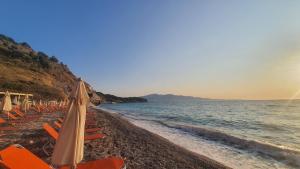 a beach with chairs and an umbrella and the ocean at Mihal Suites in Sarandë