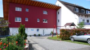 a red and white building with a car parked in front at Ferienwohnung Sonnenschein in Rheinhausen