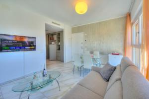 ein Wohnzimmer mit einem Sofa und einem Glastisch in der Unterkunft Attico Al Parco - Happy Rentals in Lugano