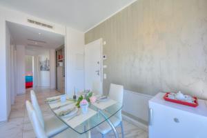 a dining room with a glass table and white chairs at Attico Al Parco - Happy Rentals in Lugano