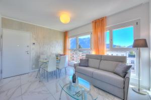 ein Wohnzimmer mit einem Sofa und einem Tisch in der Unterkunft Attico Al Parco - Happy Rentals in Lugano