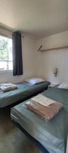 2 camas en una habitación con ventana en Camping Parc des 7 Fonts en Agde