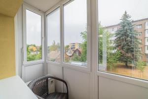 a room with three windows with a view of a tree at Frida Apartment in Šiauliai