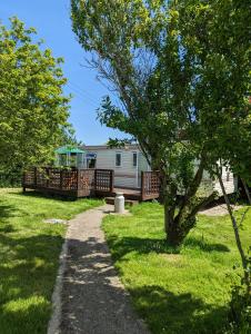 a house with a deck and a yard with a tree at Glebe Farm Holidays in Newport