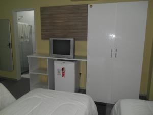 a bedroom with a bed and a tv on a counter at Titão Plaza Hotel in Campina Grande