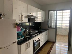 a kitchen with white cabinets and a stove at Cozy Apartment with Pool near Beach in Mohammedia