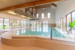 a swimming pool in a building with windows at Dormio Resort Obertraun in Obertraun