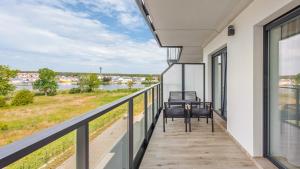 a balcony with chairs and a view of a river at Prywatne apartamenty Sun & Snow w Porta Mare Marina z basenem in Dziwnów