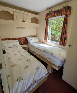 two beds in a small room with a window at Glebe Farm Holidays in Newport +7 photos