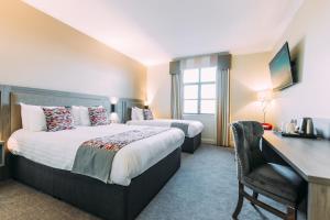 una camera d'albergo con 2 letti e una scrivania di Armagh City Hotel ad Armagh