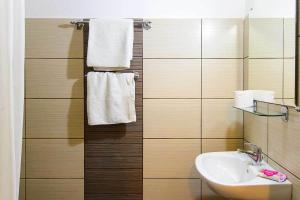 a bathroom with a sink and a mirror and towels at Galanopoulos Hotel in Loutraki