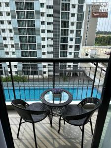 a balcony with a table and chairs and a pool at Teratak Desaru Homestay Wi-fi, Smart TV & Water Dispenser in Bandar Penawar