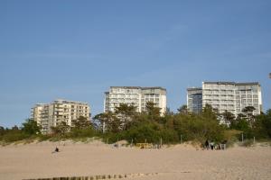 a beach with two tall buildings in the background at M&M Apartament Dziwnówek (z widokiem na morze) in Dziwnówek