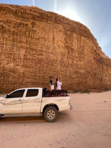 two people standing on the back of a white truck at Zarb Desert Camp in Wadi Rum