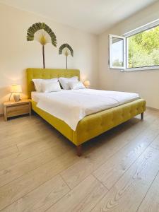 a bedroom with a large bed with a yellow headboard at TINEL Boutique Apartment in Promajna