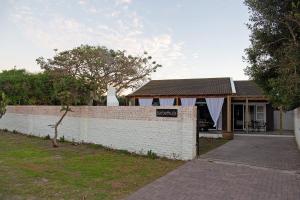 a house with a white brick wall next to a driveway at Barbethuijs in Jeffreys Bay