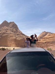 Due persone che scattano foto di un'auto nel deserto. di Zarb Desert Camp a Wadi Rum