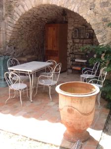an outdoor patio with a table and chairs and a pot at Gîte La Manhanéra in Bouquet +16 photos