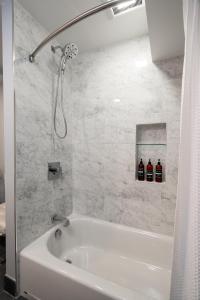 - une baignoire blanche avec douche et 2 bouteilles de bière dans l'établissement Bassett Creek Retreat, à Minneapolis