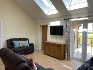 a living room with a couch and a flat screen tv at The Haystack Lodge in Tarporley
