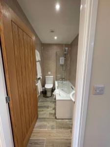 a bathroom with a toilet and a tub and a sink at The Haystack Lodge in Tarporley