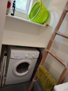 une buanderie avec un lave-linge et un plateau vert sur une étagère dans l'établissement Maison de charme, à Audenge