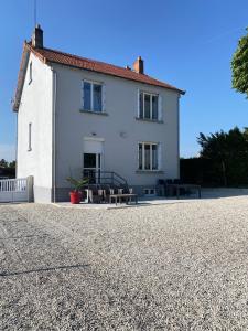 a white house with two benches in front of it at O' li douillet in Les Épesses