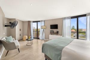a bedroom with a bed and a chair and a television at Suites Boulevard 17 in Vlissingen