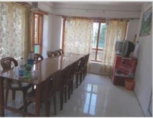 comedor con mesa, sillas y TV en Fiza Guest House, Pahalgam, en Pahalgām