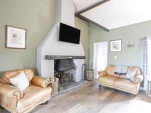 a living room with two chairs and a fireplace at The Keepers Lodge in Pwllheli