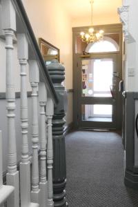 a hallway with a staircase with a door and a chandelier at Sunnydene in Great Yarmouth