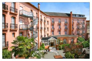 a large pink building with a spiral staircase in front of it at Hôtel Métropole in Lourdes
