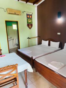 a room with two beds and a bathroom with a shower at Hareesha Holiday Resort in Galle