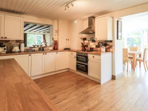 a kitchen with white cabinets and a wooden floor at Ellerbeck Bridge in Kendal