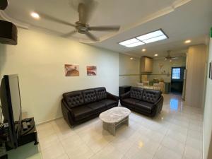 a living room with a couch and a tv at Happiness Homestay in Mersing