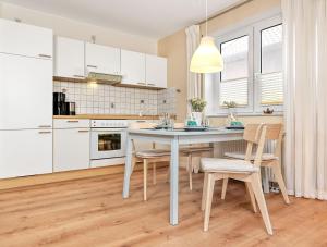 uma cozinha com armários brancos e uma mesa e cadeiras em Haffblick em Insel Poel
