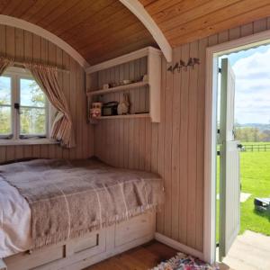 Skylark Shepherds Hut في رويال تونبريدج ويلز: غرفة نوم بسرير ونافذة