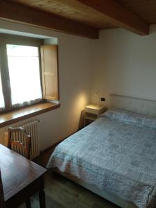 a bedroom with a bed and a table and a window at La Pace della Montagna alle Porte della Città in Aosta