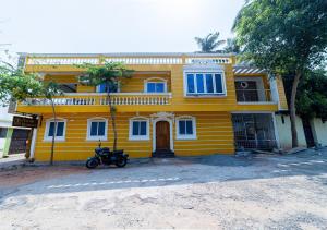 une maison jaune avec une moto garée devant elle dans l'établissement Yellow Residency, à Pondichéry