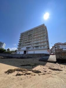 un edificio en la playa con el sol en el cielo en Apartamento Arousa Mar, en Villanueva de Arosa