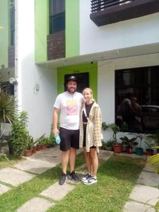 un homme et une femme debout devant un bâtiment dans l'établissement Haus of Emerald by JeYo, à Mactan