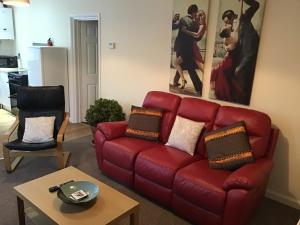 a living room with a red couch and a table at Frankies Flat, a Superb apartment in Flamborough. in Flamborough
