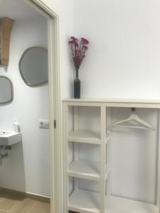 uma casa de banho com uma prateleira branca com um vaso de flores em Encantadora casa rural Can Vidal em Espolla