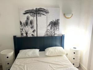 a bed with a blue headboard with palm trees on it at Les yeux dans l'océan in Le Croisic