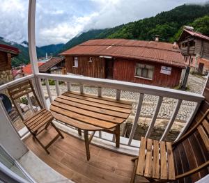 eine Holzbank auf einem Balkon mit einem Haus in der Unterkunft Suit Rabando Uzungöl in Uzungöl