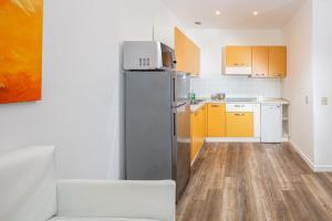 cocina con nevera y armarios amarillos en Monaco Apartments, en Lignano Sabbiadoro